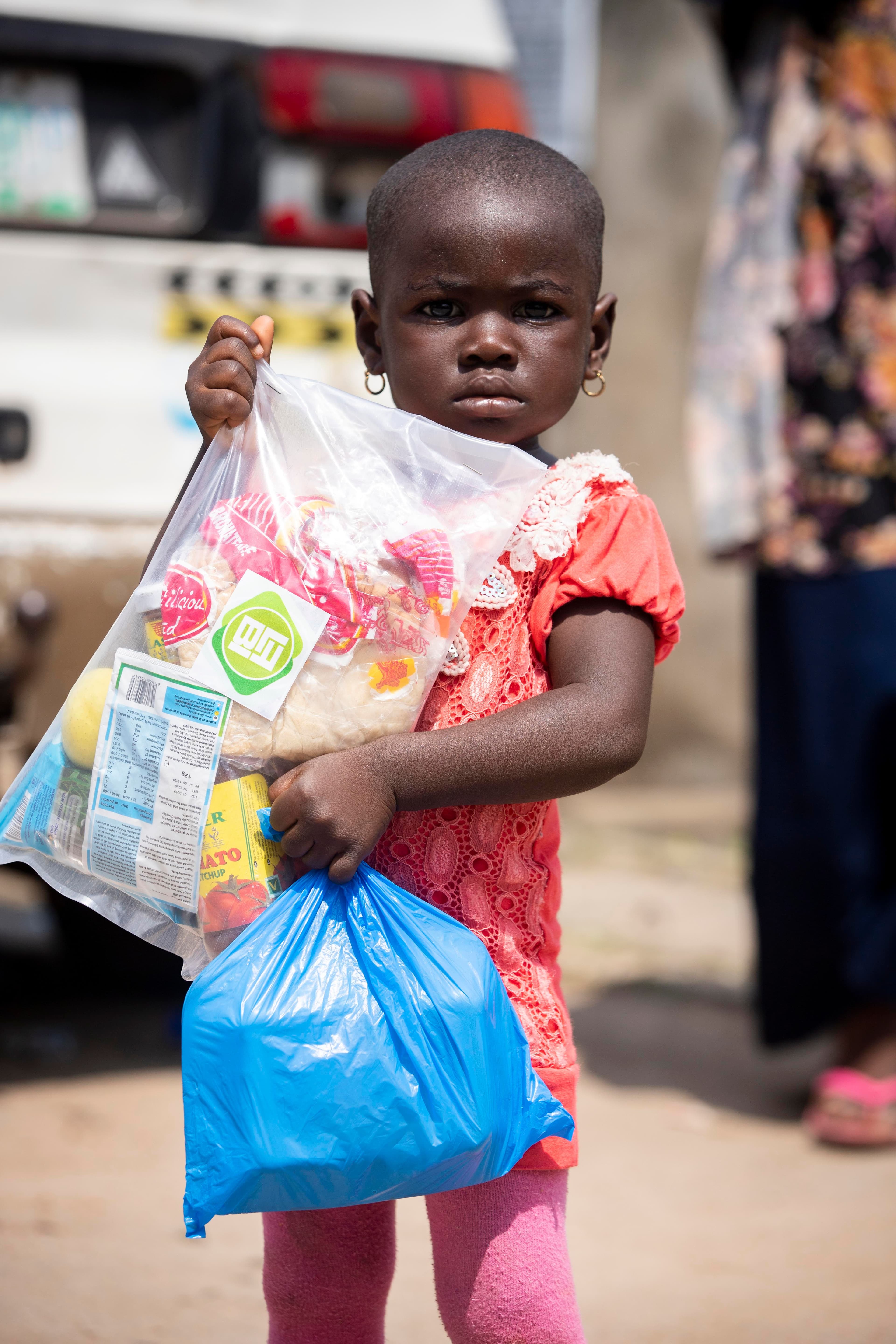 Young child holding bags of food support